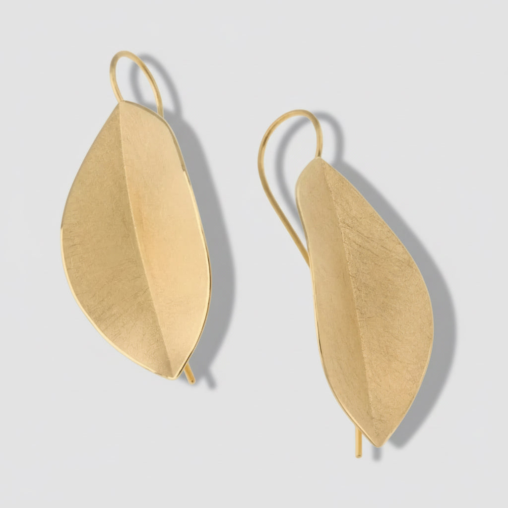Gold leaf-shaped earrings on a white background