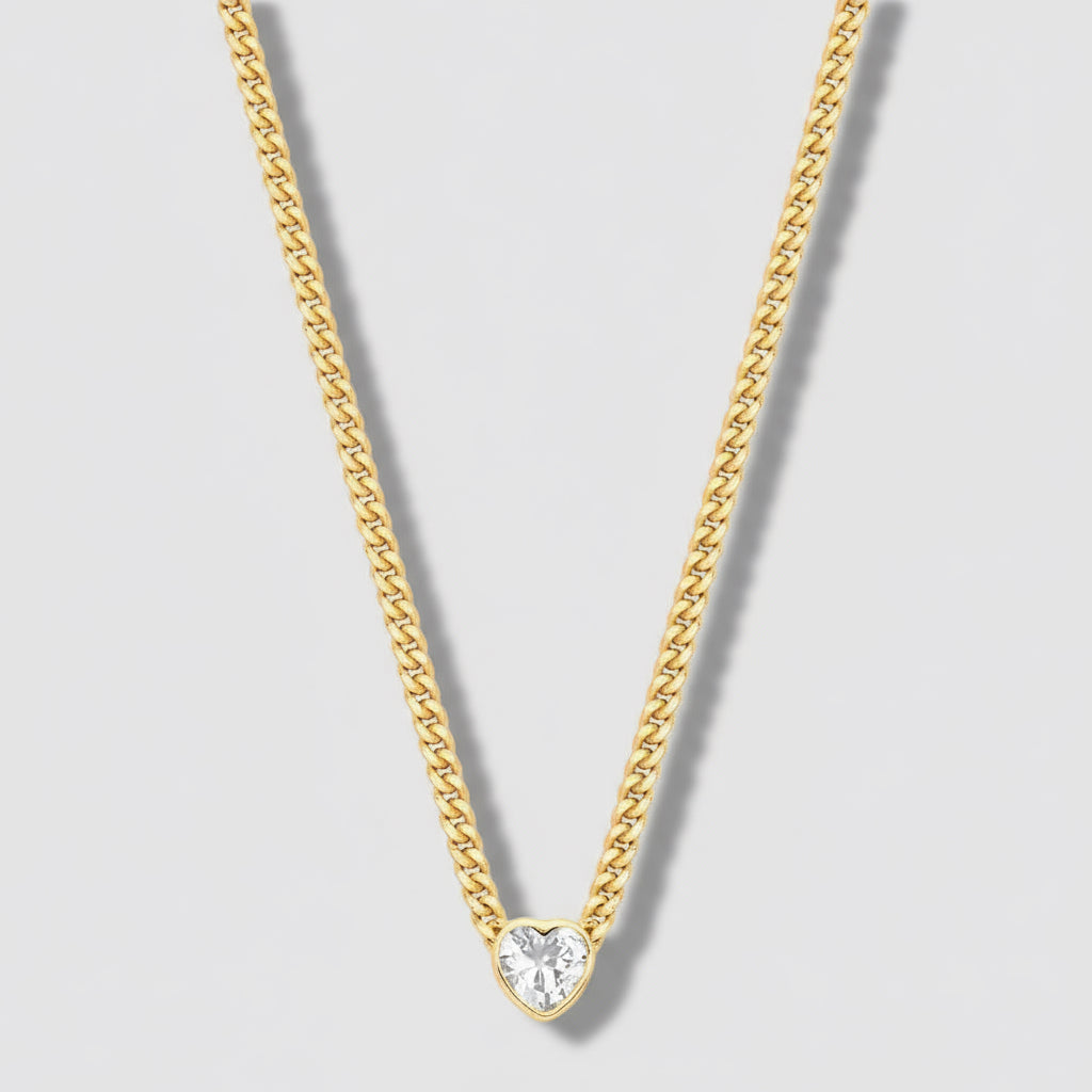 Gold chain necklace with a heart-shaped pendant on a light gray background