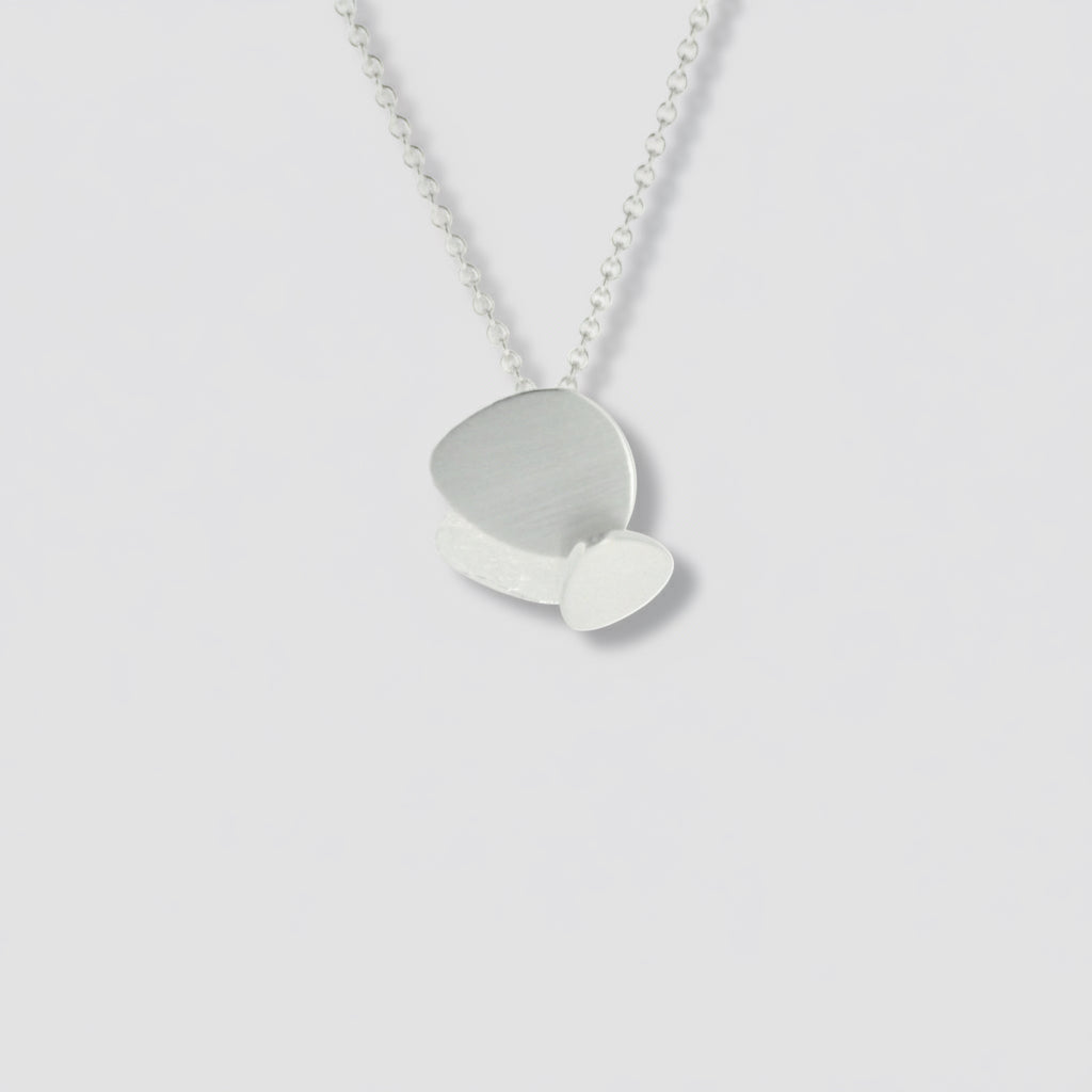 A sterling silver geometric pendant necklace with a silver chain and a layered circular pendant