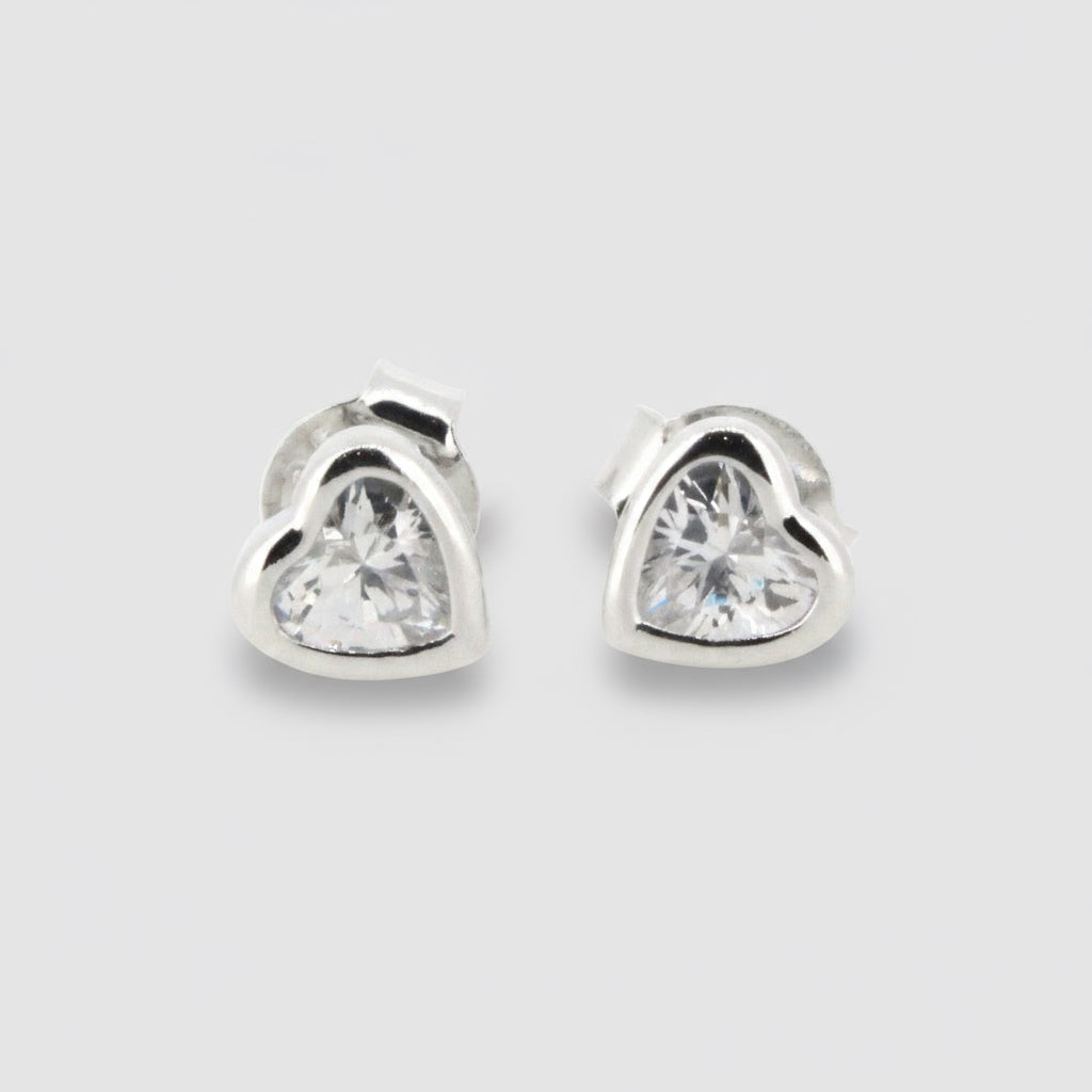 A pair of sterling silver heart-cut cubic zirconia stud earrings against a white background.