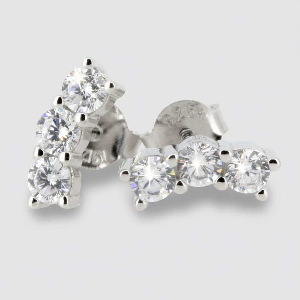 A pair of sterling silver stud earrings featuring three round cubic zirconia stones arranged in a curved pattern.