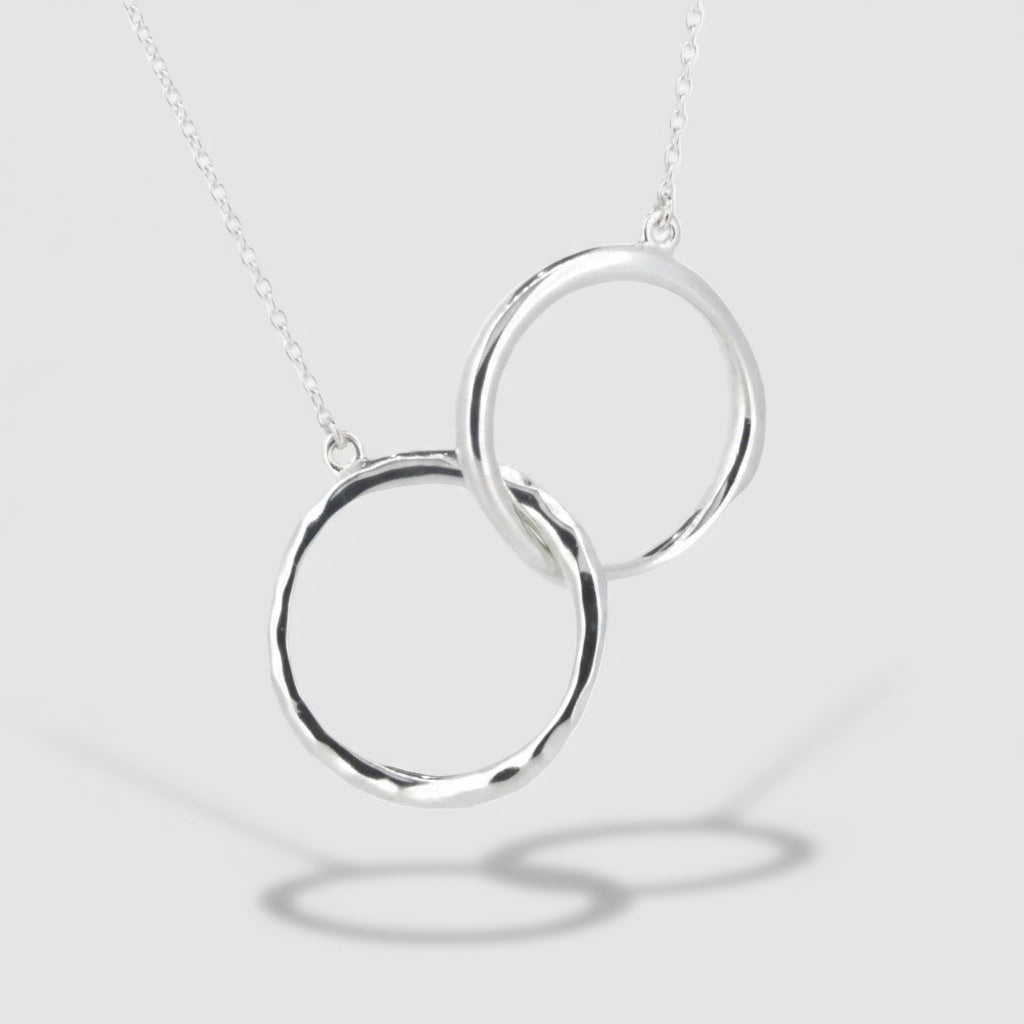 A sterling silver necklace featuring two interlocking circle pendants on a chain.