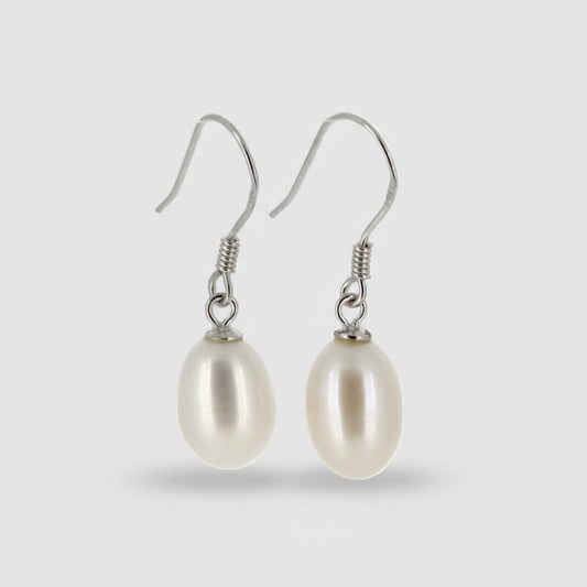 Pearl earrings with silver hooks on a light gray background
