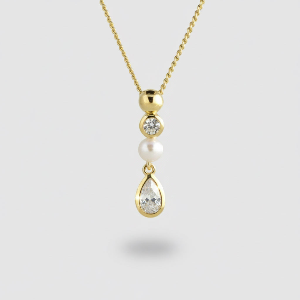 Gold necklace with a pendant featuring a pearl and two gemstones on a light gray background