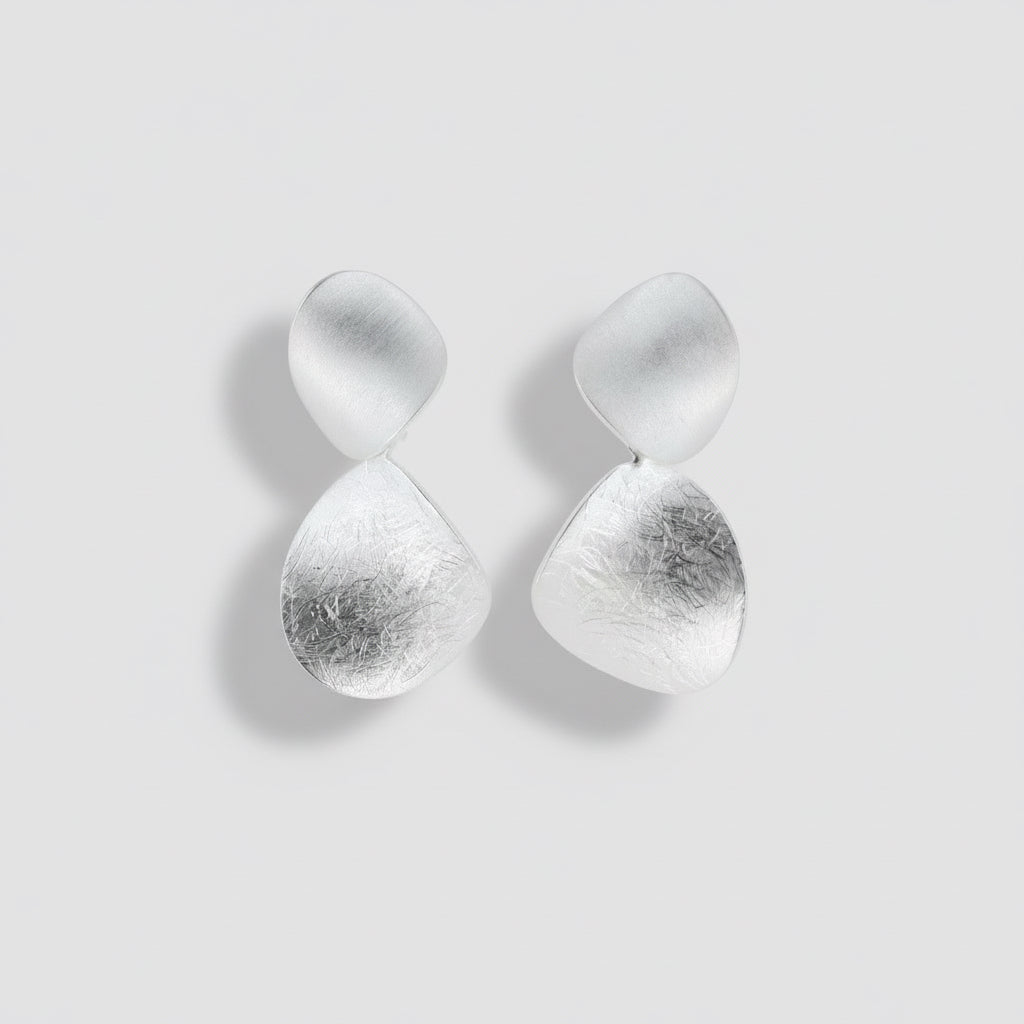 Pair of silver earrings on a light gray background.