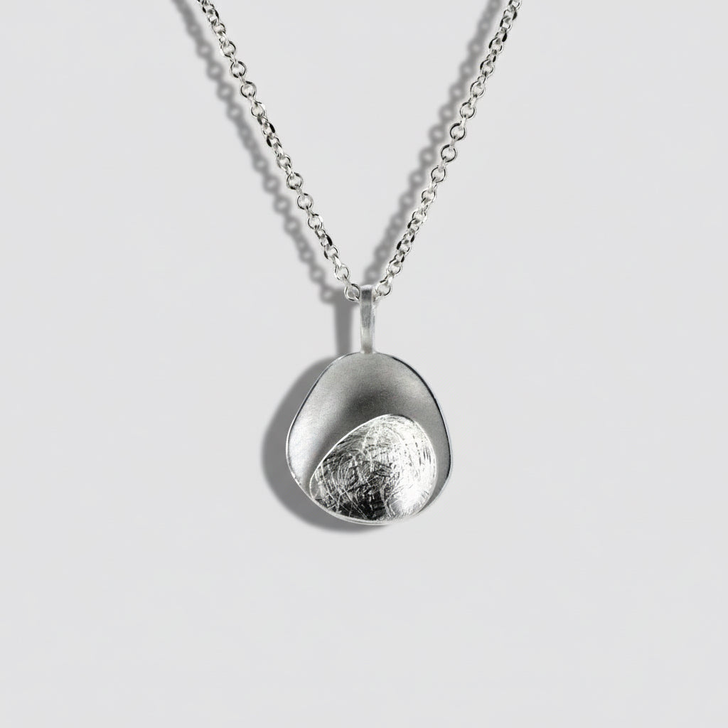 Silver necklace with a unique pendant on a light gray background