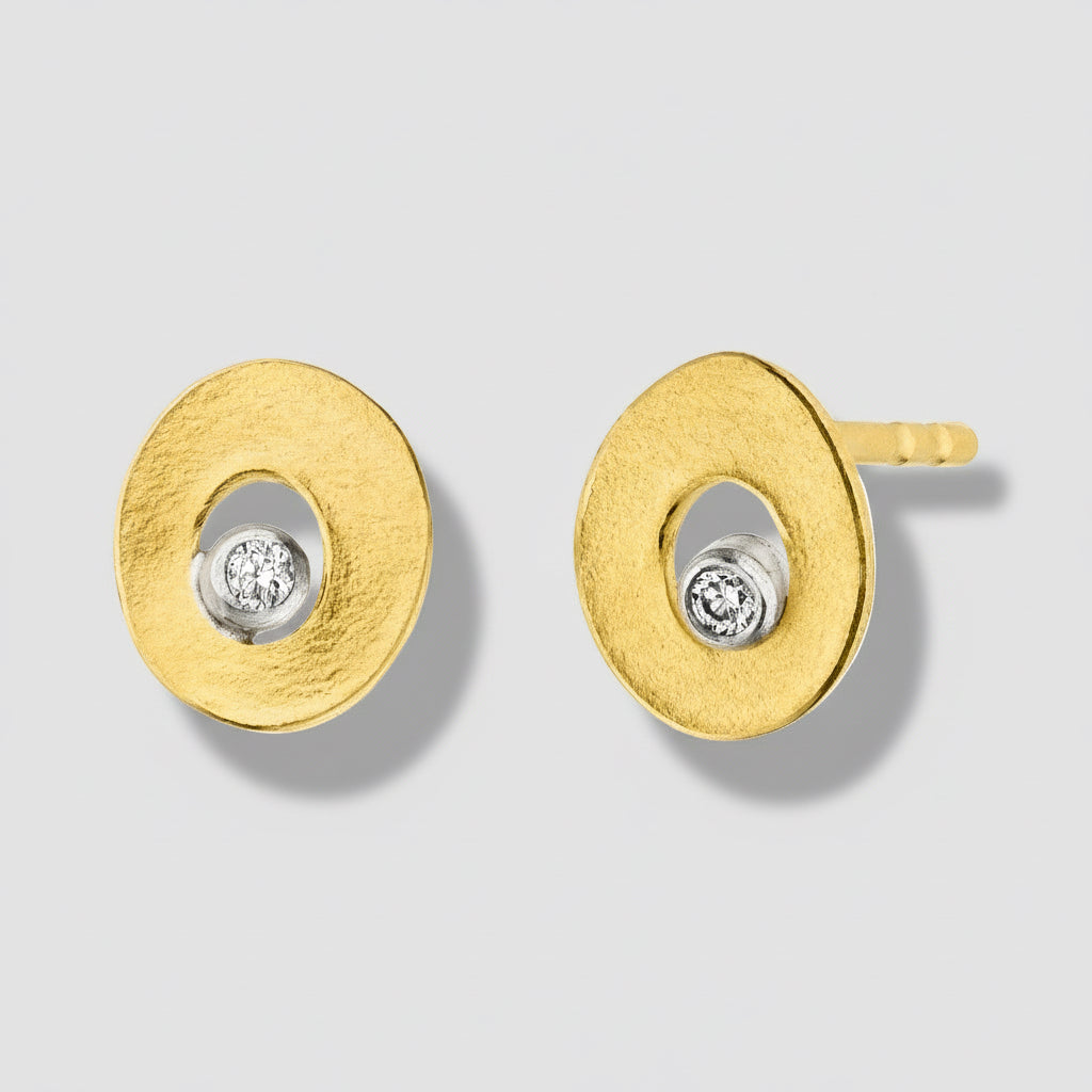 Gold earrings with circular design and embedded diamonds on a white background