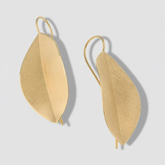 Gold leaf-shaped earrings on a white background