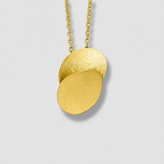 Gold necklace with two round pendants on a white background