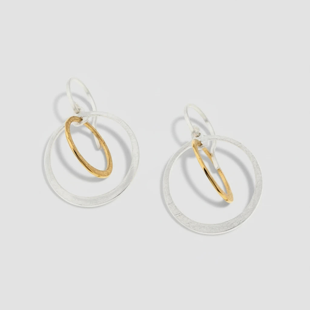 Pair of earrings with gold and silver circular designs on a white background