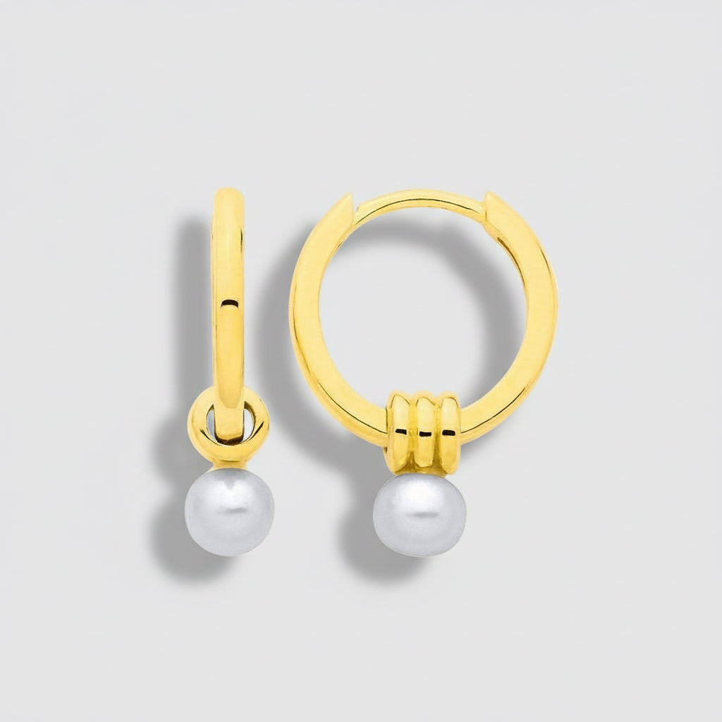 Gold hoop earrings with pearls on a light gray background