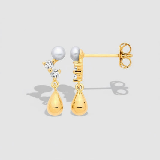 Gold earrings with pearls and teardrop shapes on a light gray background