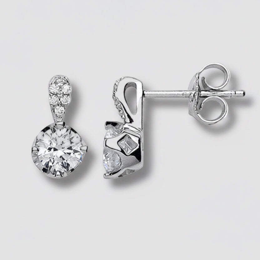 Pair of silver earrings with clear gemstones on a light gray background