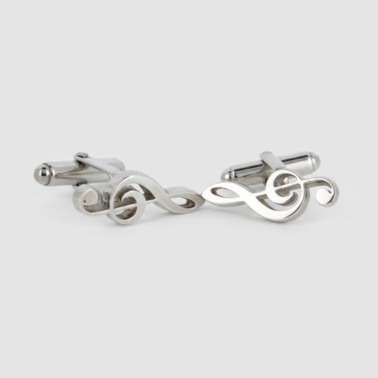 Pair of silver treble clef cufflinks on a light gray background