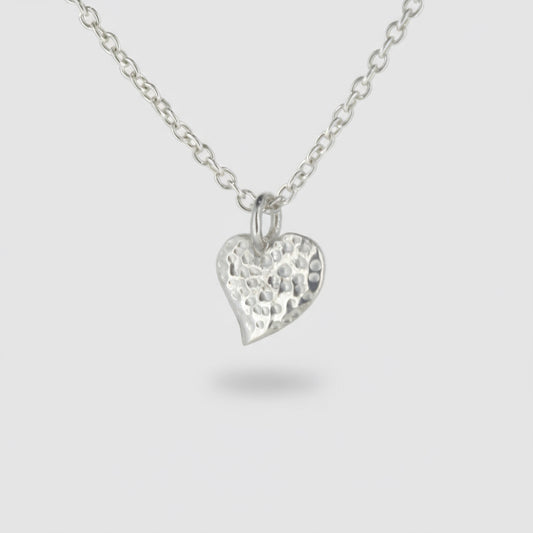 Silver heart-shaped pendant on a chain against a white background
