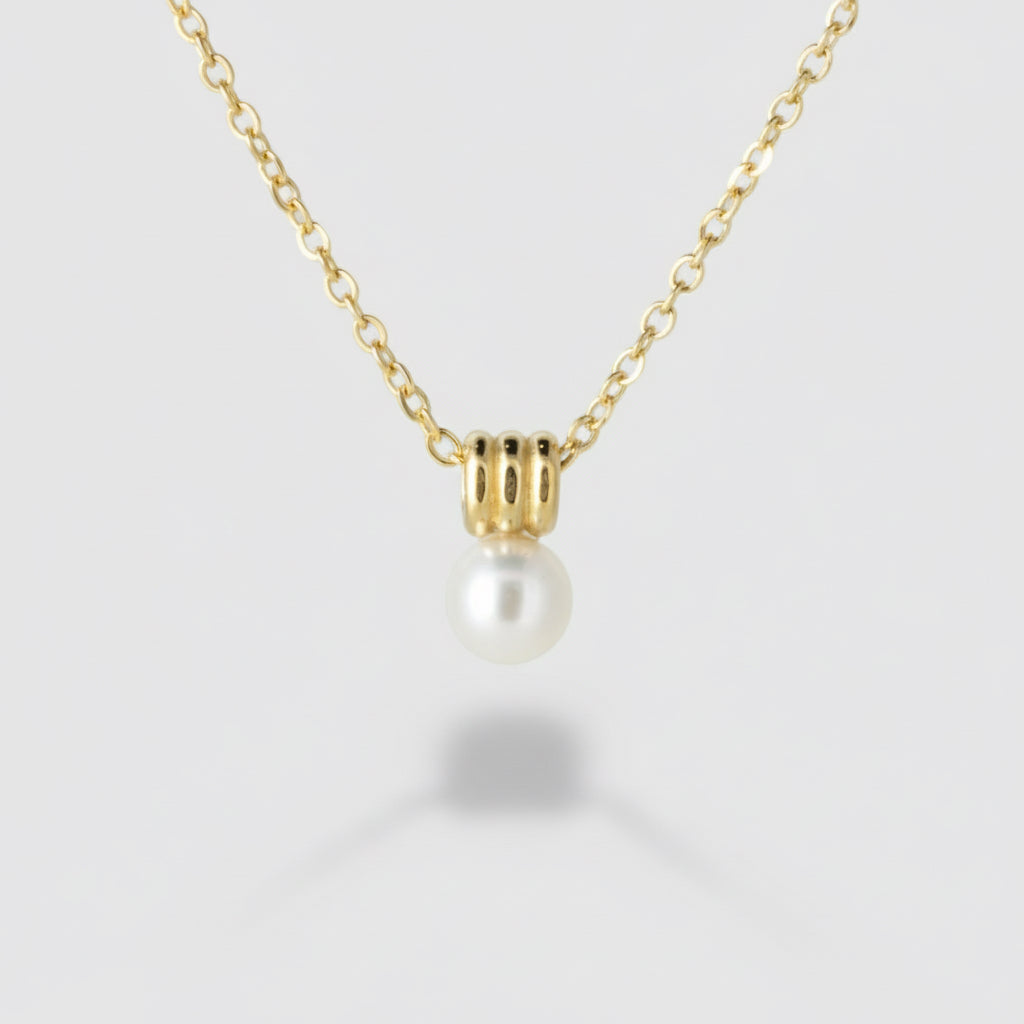 Gold necklace with a pearl pendant on a light gray background