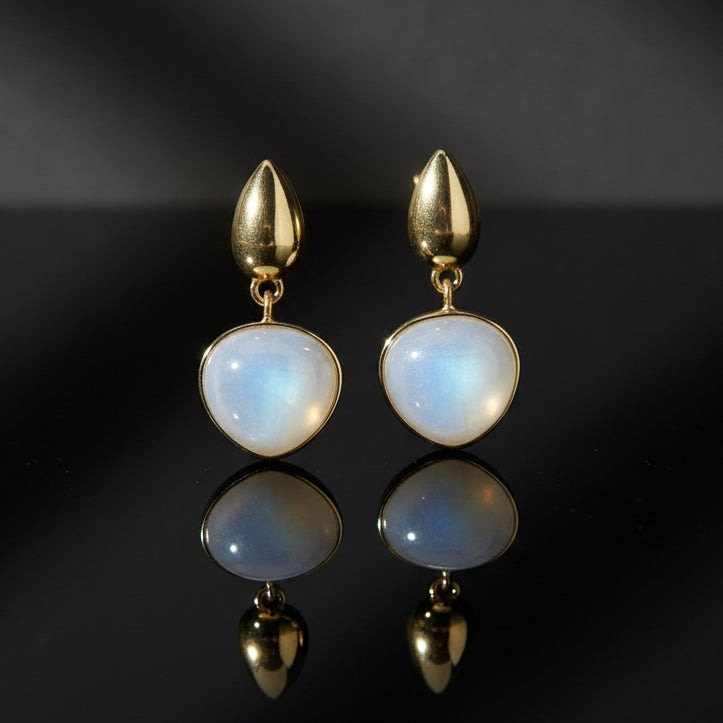 Gold earrings with white stones on a light gray background