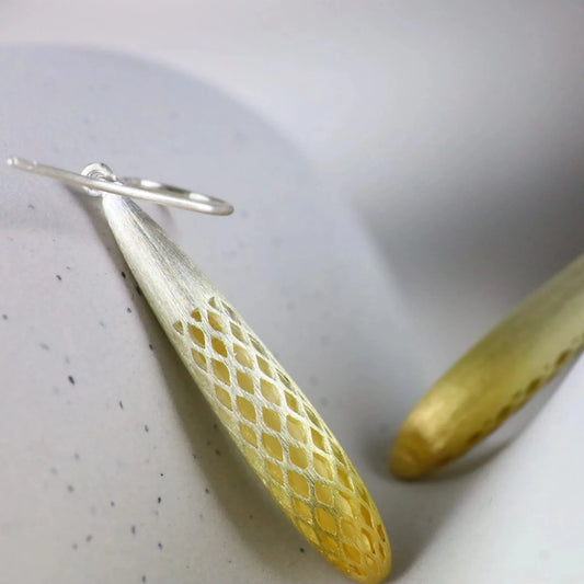 Gold and silver earrings on a textured surface