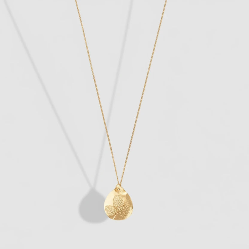 Gold necklace with a textured pendant on a white background
