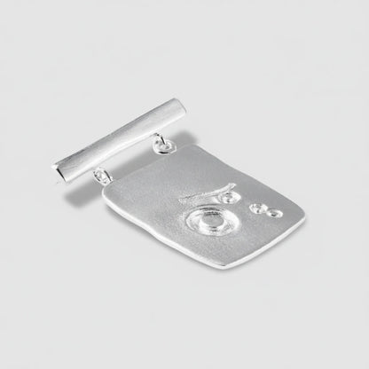 Silver brooch with a detailed design on a white background