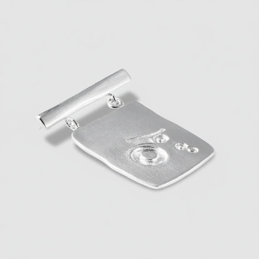 Silver brooch with a detailed design on a white background