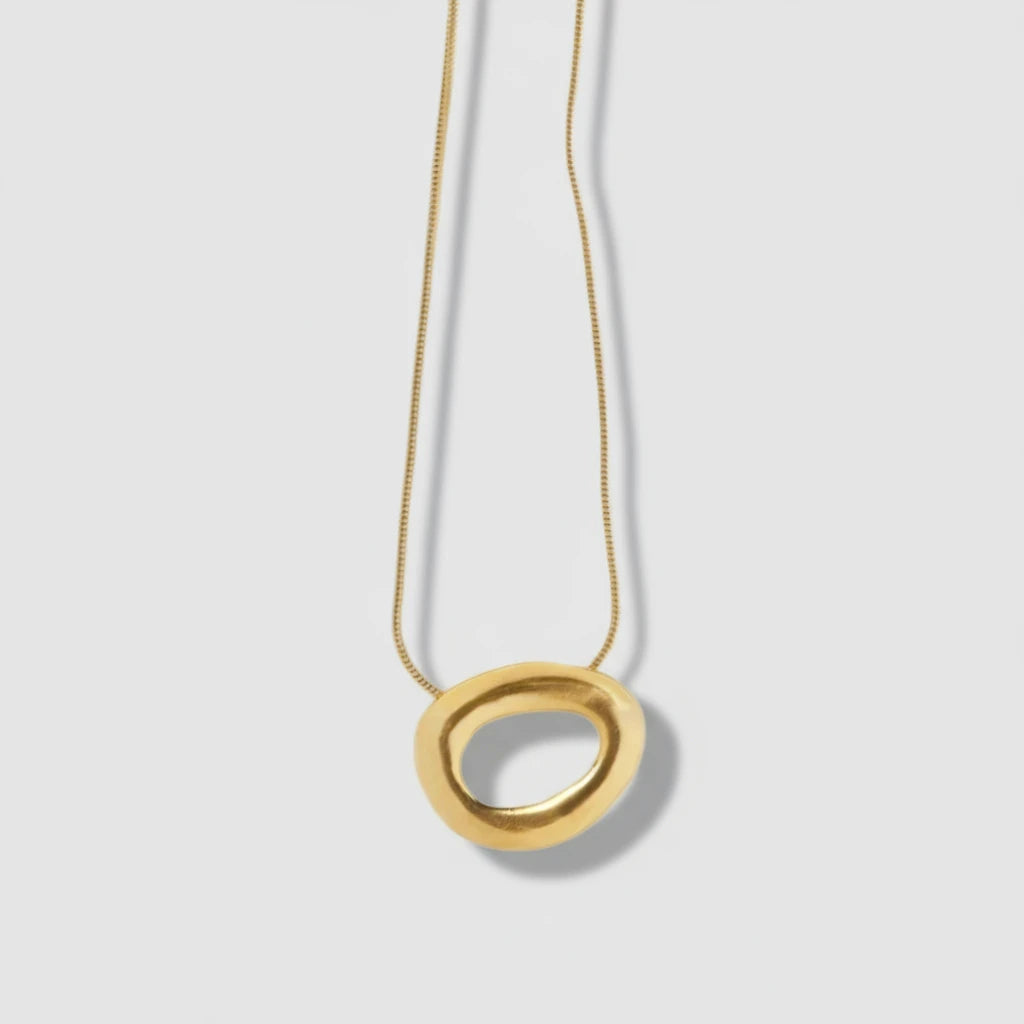 Gold necklace with a circular pendant on a white background