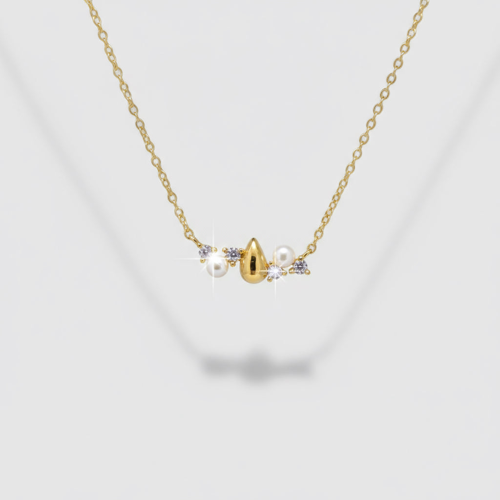 Delicate gold necklace with small pearls and a heart pendant on a light gray background