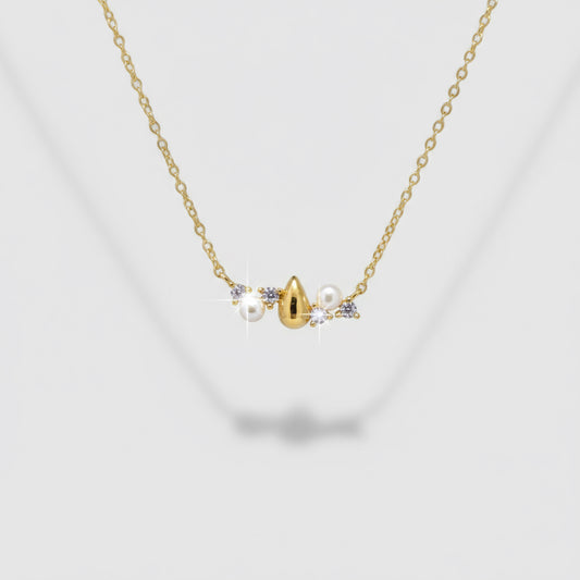 Delicate gold necklace with small pearls and a heart pendant on a light gray background