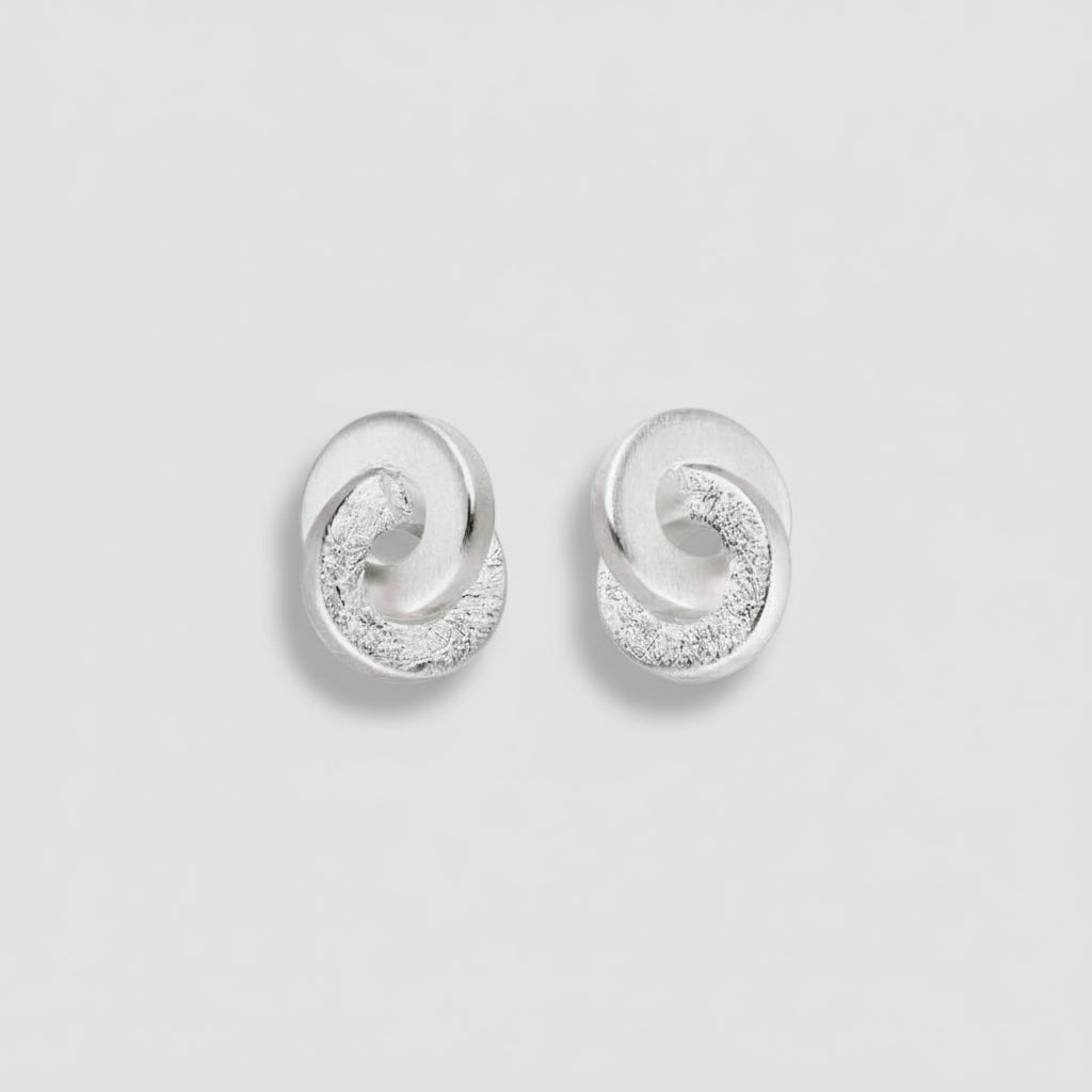 Pair of silver earrings with circular design on a white background