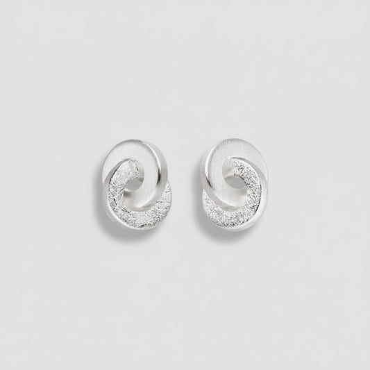 Pair of silver earrings with circular design on a white background