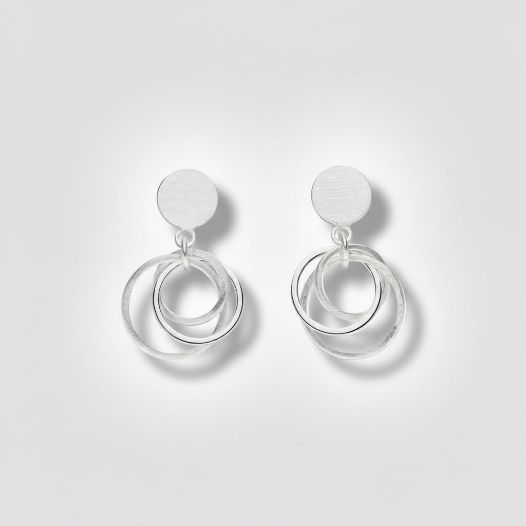 Pair of silver earrings with circular designs on a white background