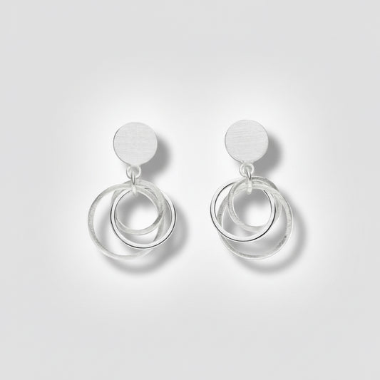 Pair of silver earrings with circular designs on a white background