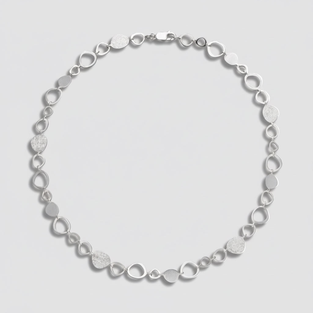 Silver bracelet with circular links on a white background