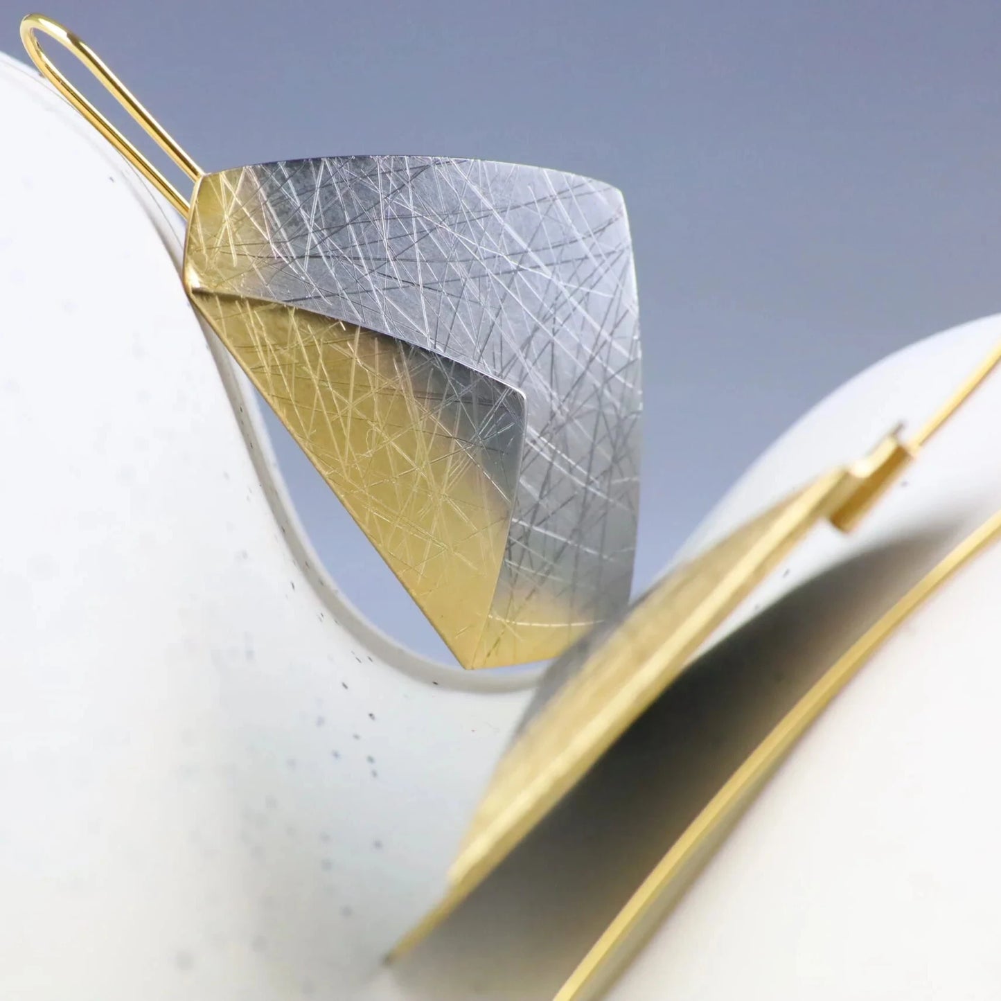 Gold and silver leaf-shaped earrings on a light background