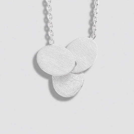 Silver necklace with three round pendants on a white background
