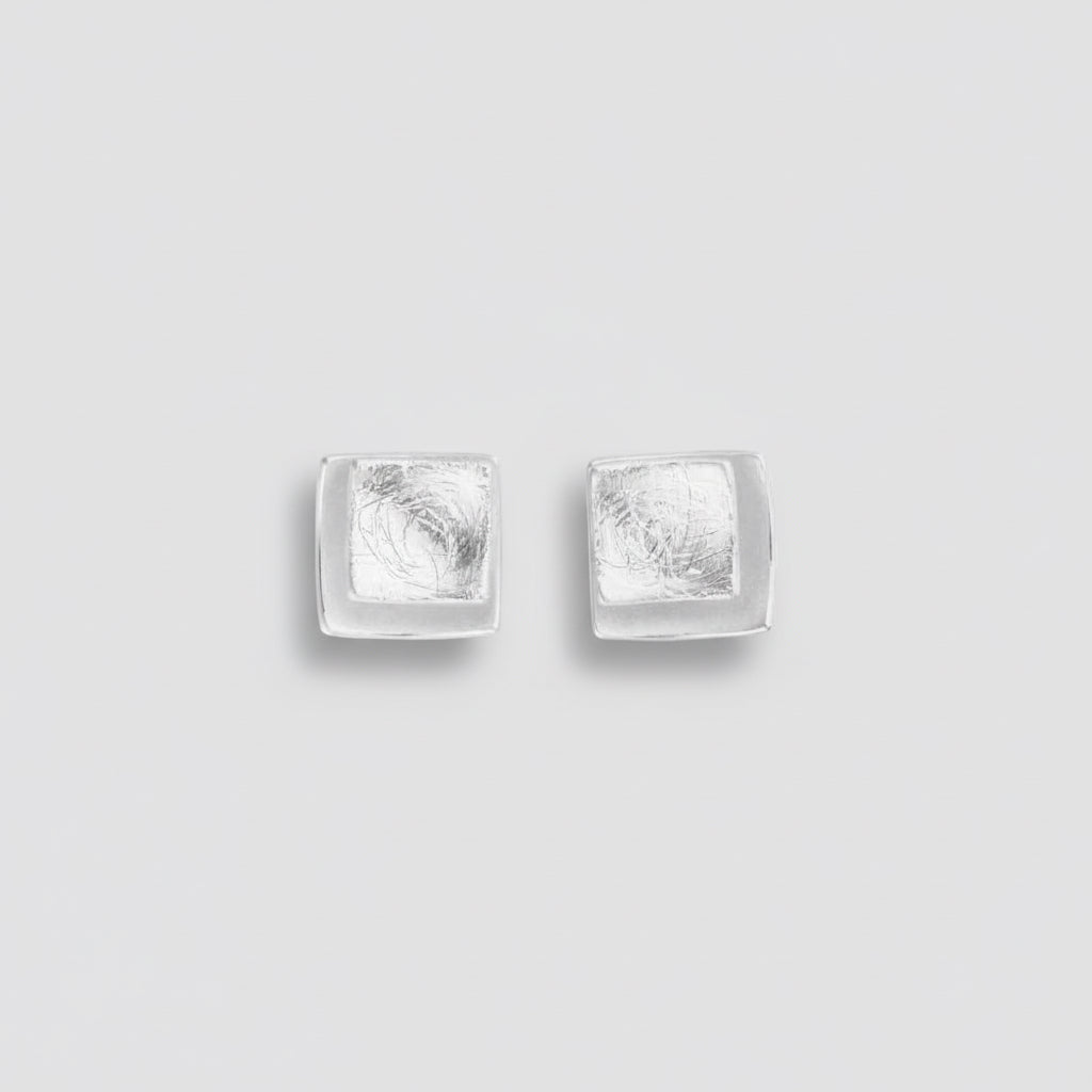 Pair of silver square stud earrings on a white background