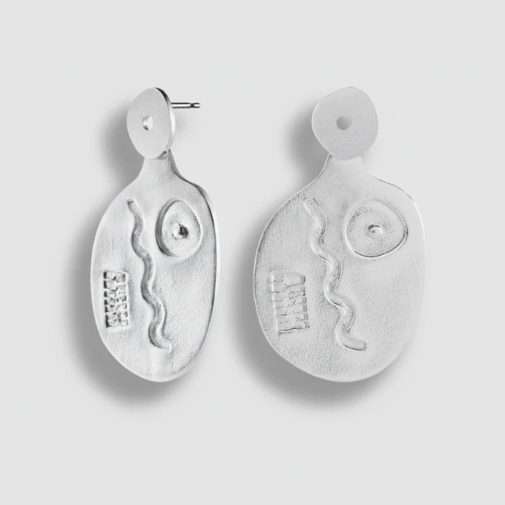 Pair of silver earrings with abstract designs on a light gray background