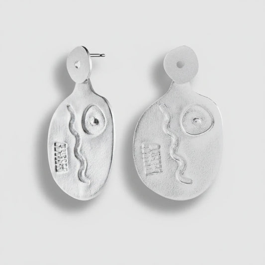 Pair of silver earrings with abstract designs on a light gray background